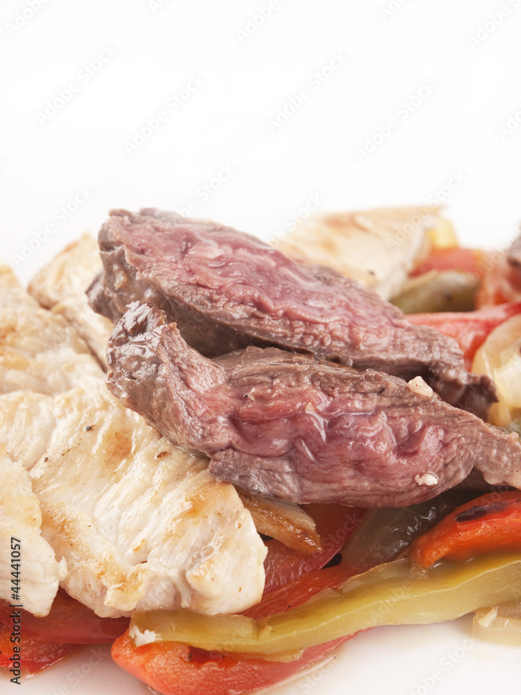 Pollo y carne cortado en tiras con pimientos sobre un fondo blanco. Vista de frente