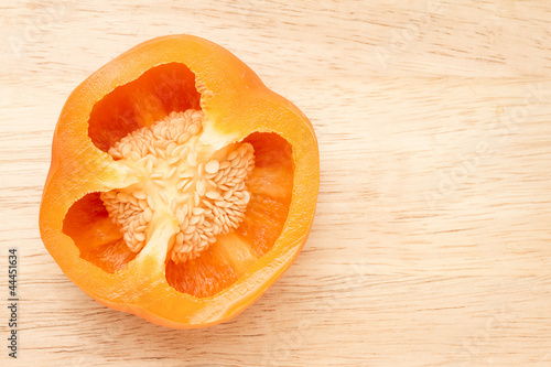 Half of an orange pepperon wooden choppng block photo