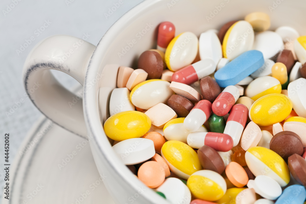 White cup filled with medicine pills and capsules White cup filled with medicine pills and capsules