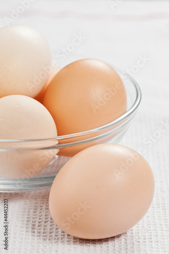Fresh raw organic eggs in a glass bowl on the white cloth