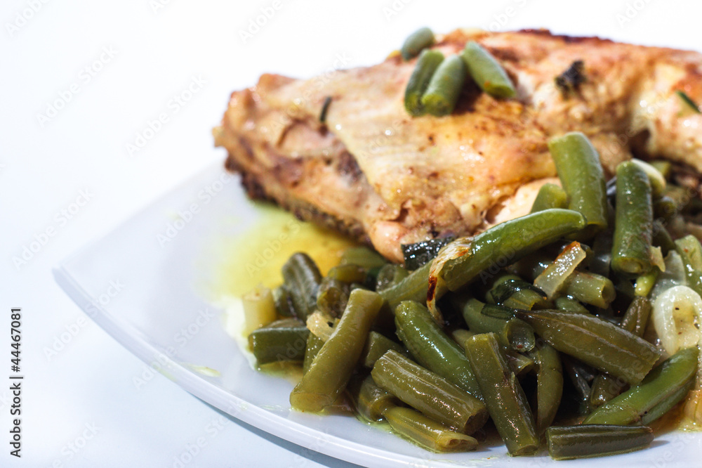 Fried chicken leg with french beans on white plate.