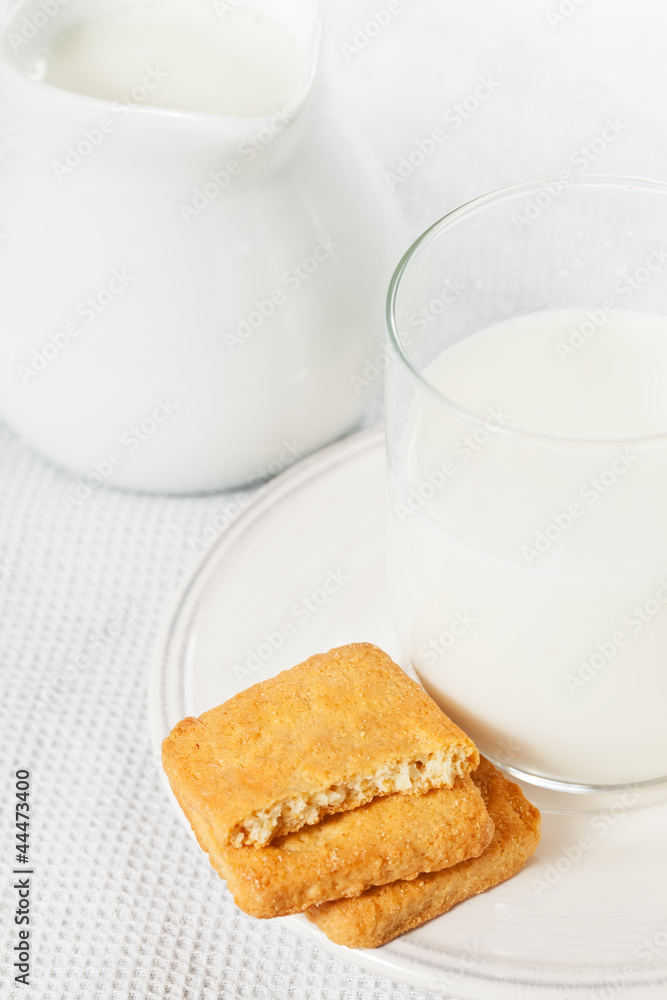 Half a glass of milk on the plate with cookies and a jug of milk Half a glass of milk on the plate with cookies and a jug of milk