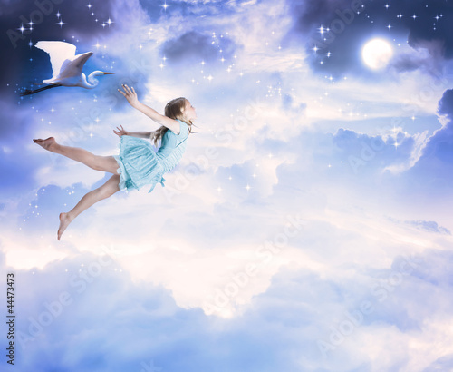 Little girl flying into the blue night sky