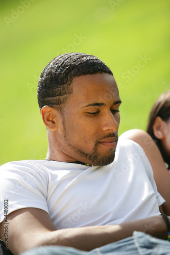 Young man relaxing on the grass with friends