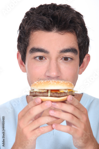 Young man facing a hamburger