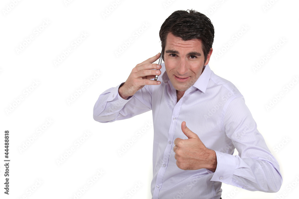 A businessman over the phone giving the thumb up. A businessman over the phone giving the thumb up.