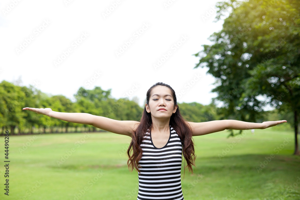 Young woman arms raised enjoying the fresh air in the park Young woman arms raised enjoying the fresh air in the park