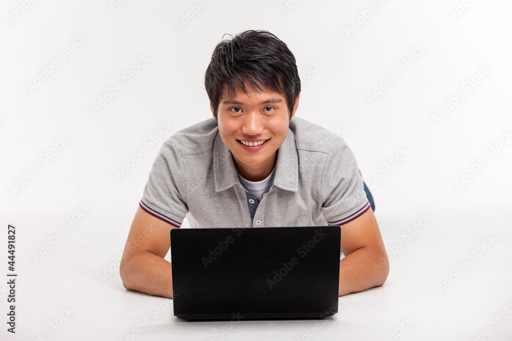 A smiling male working on a laptop isolated on white background A smiling male working on a laptop isolated on white background