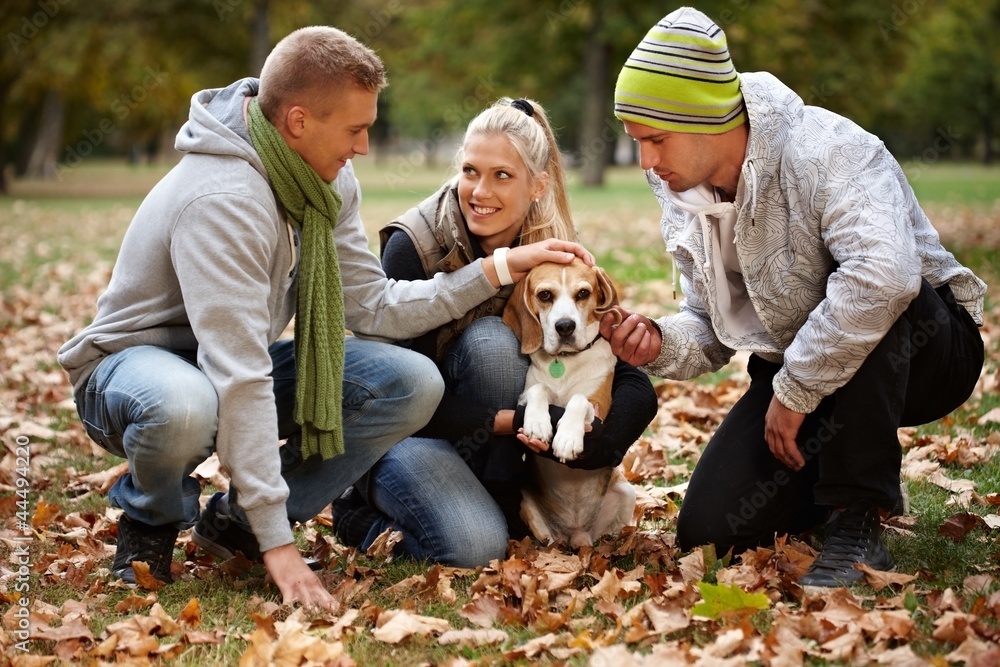 Fototapeta premium Young people and dog in autumn park