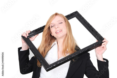 Pretty woman putting her head through a picture frame