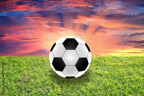 football in green grass over a sunset sky