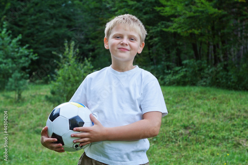 Boy football player with ball on nature.