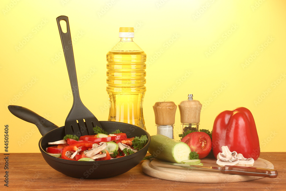 frying pan with vegetables on yellow background frying pan with vegetables on yellow background