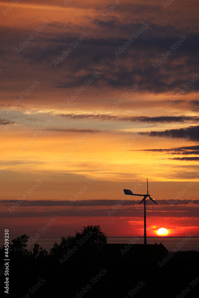 Obraz premium Small private windtubine stands in enjoyable sunset