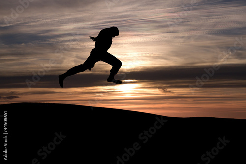silhouette of boy jumping in sunset