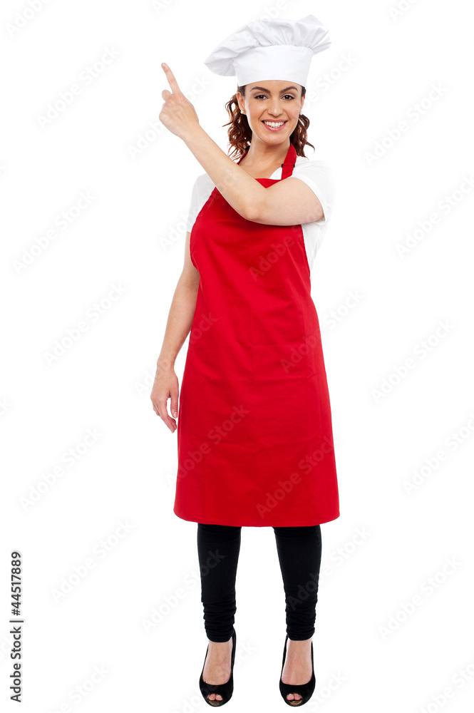 Full length portrait of female chef pointing away Full length portrait of female chef pointing away