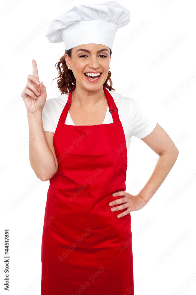 Beautiful smiling female chef indicating upwards Beautiful smiling female chef indicating upwards