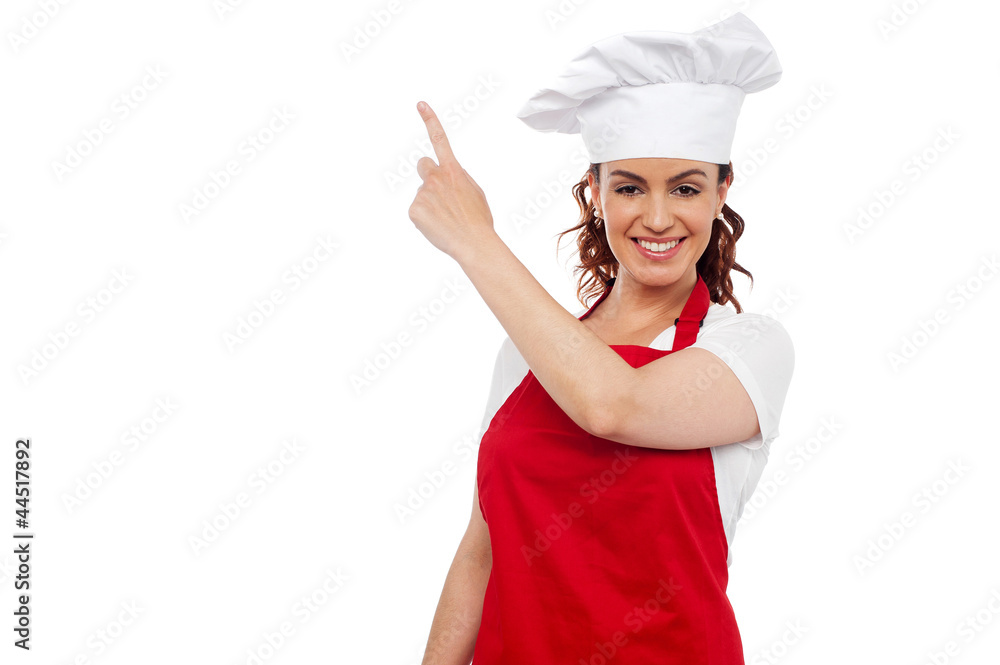 Attractive female chef pointing at copy space Attractive female chef pointing at copy space