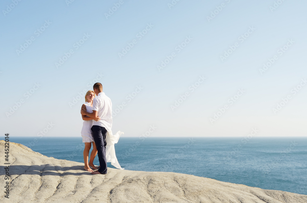 Young couple standing on rock by the sea and talking