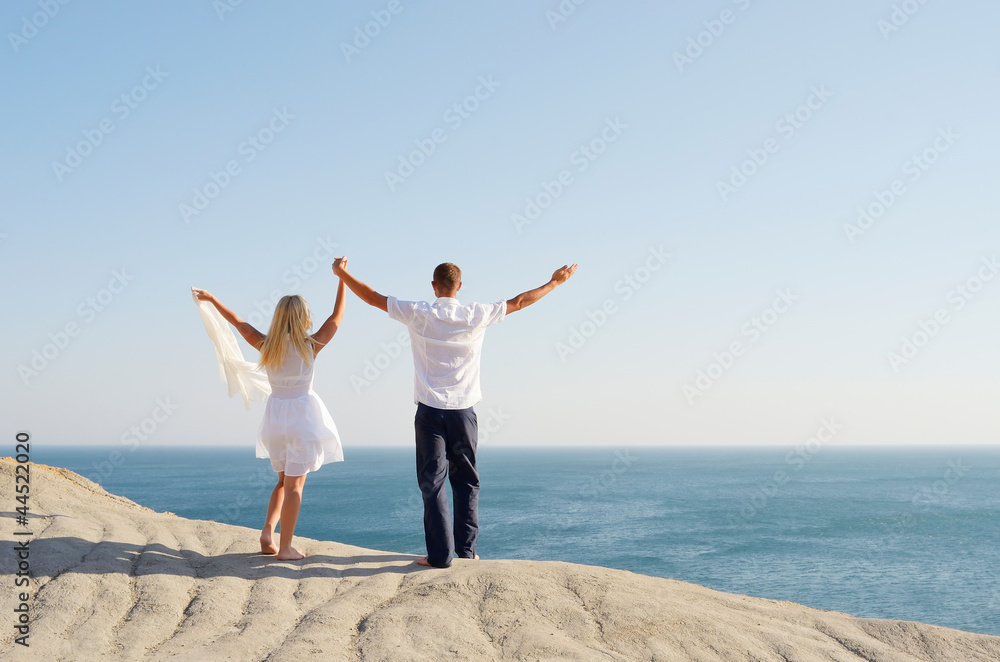 Young couple on a rock raised hands to the sky Young couple on a rock raised hands to the sky