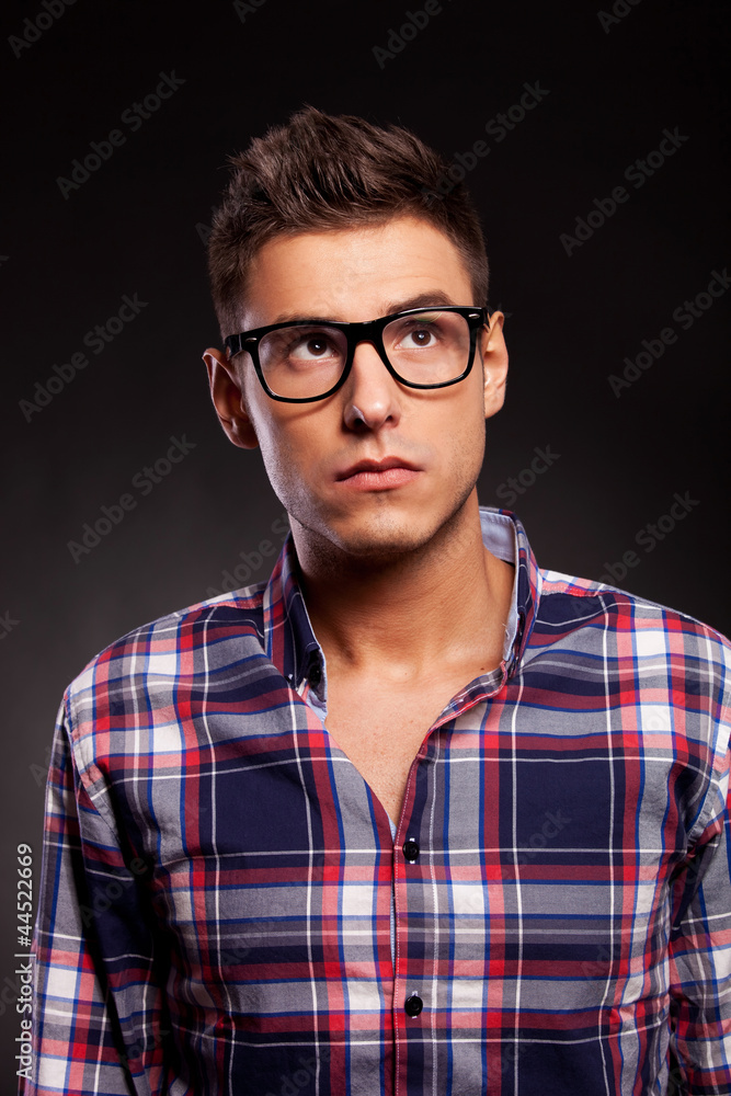 Obraz premium Young casual man wearing glasses and looking up