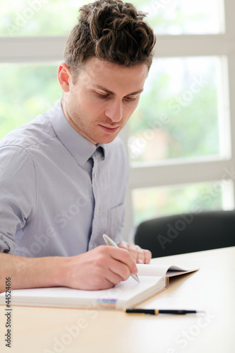 Young adult man writing note
