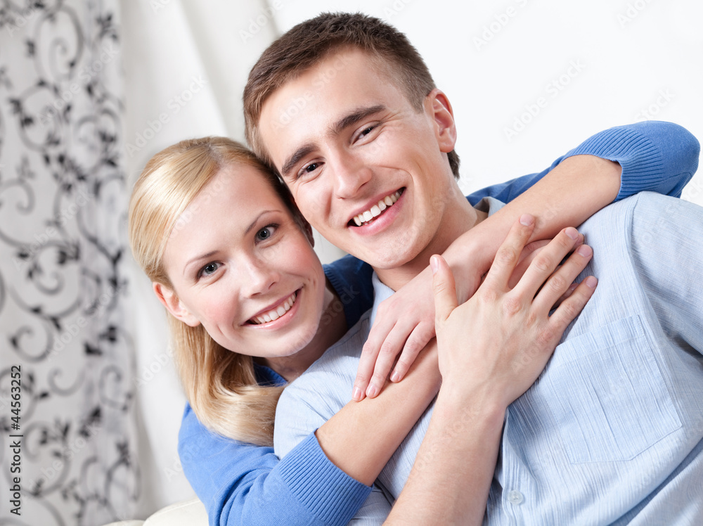 Happy couple sits on the couch hugging each other Happy couple sits on the couch hugging each other