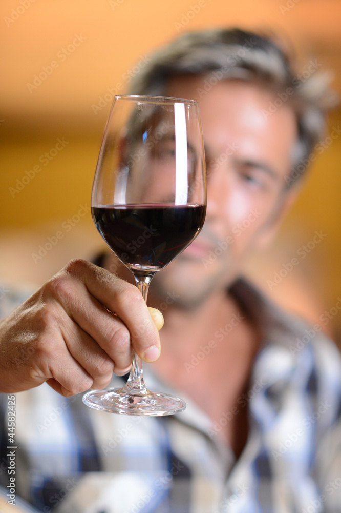 Focus on glass of red wine hold by winemaker Focus on glass of red wine hold by winemaker