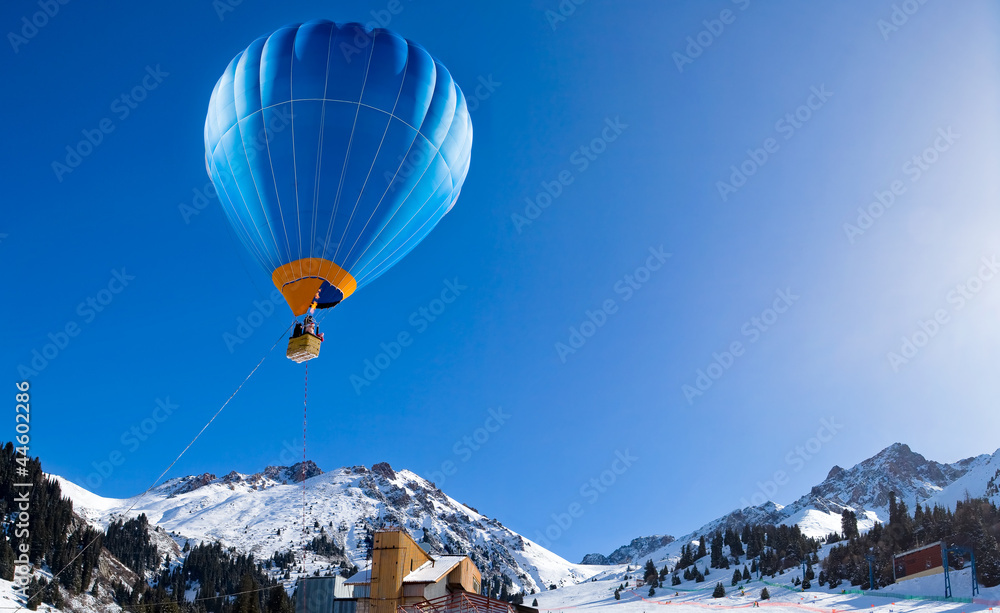 Fototapeta premium Balonowy latanie nad pasmem górskim przy jasnym niebieskim niebem