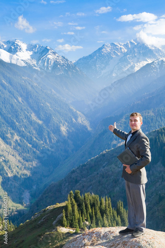 businessman with laptop at the top of the mountain