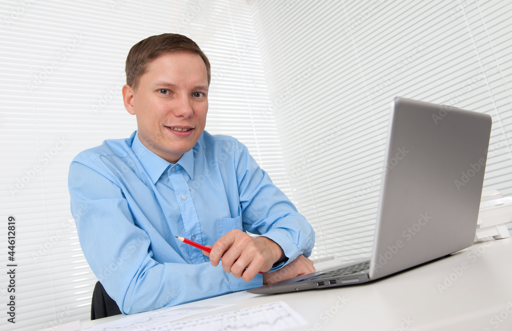 Young businessman working in office, sitting at desk with laptop Young businessman working in office, sitting at desk with laptop