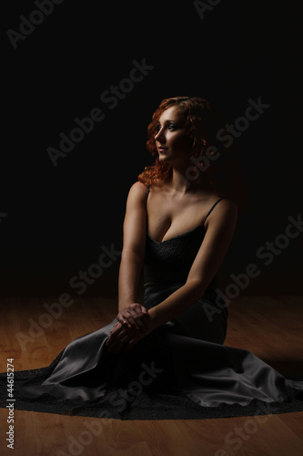 beautiful girl in a long dress is sitting in the dark