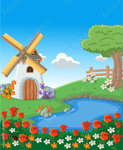 Green garden with beautiful spring flowers, lake and windmill