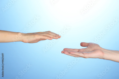 Women's hand goes to the man's hand on blue background