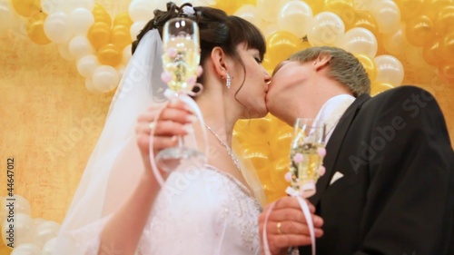 Newly-married couple kisses champagne glasses in hands