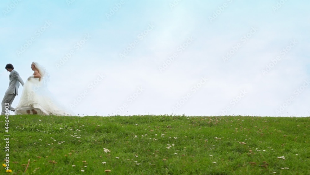 Newly-married couple runs on grass keeping for hands Newly-married couple runs on grass keeping for hands