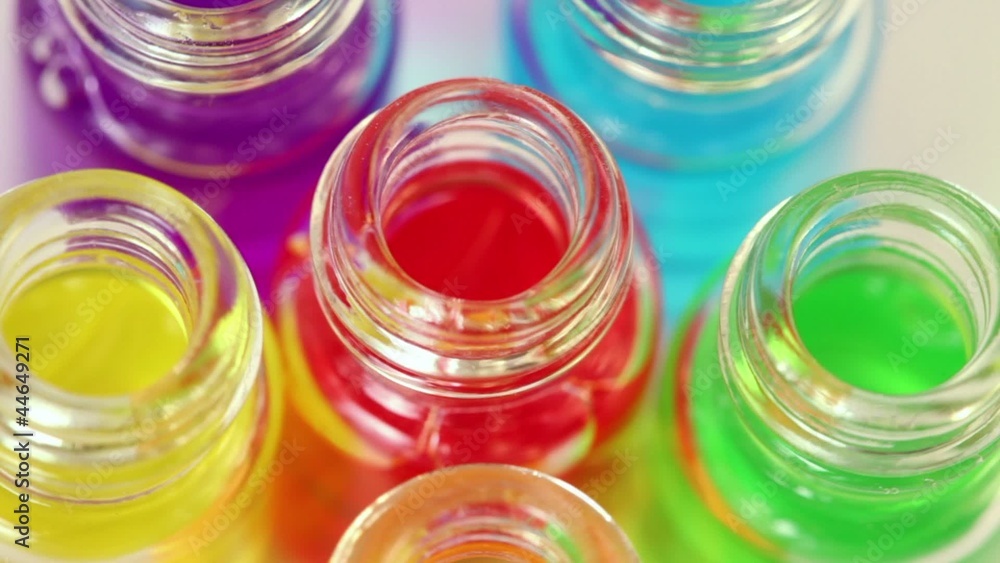 Six transparent open bottles rotates with color oil on them Six transparent open bottles rotates with color oil on them