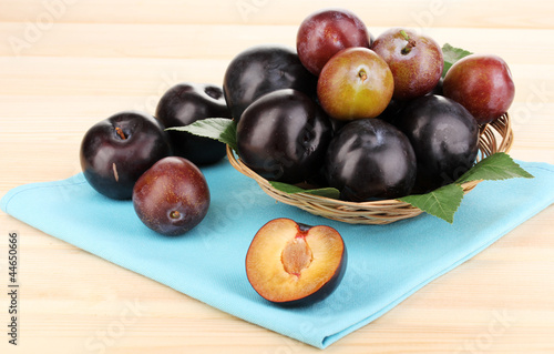 Rip plums on basket on wooden table