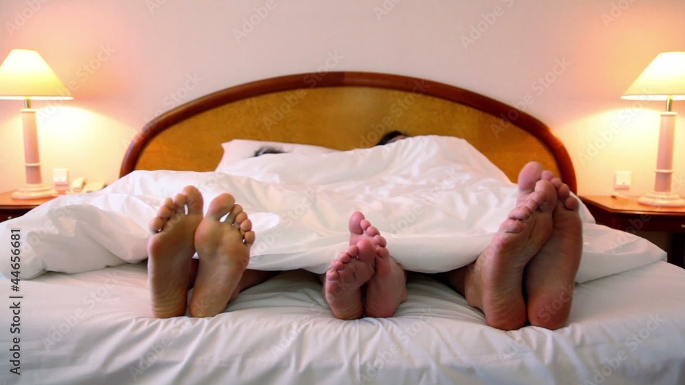 parents with son lay in bed and move shoeless feet parents with son lay in bed and move shoeless feet