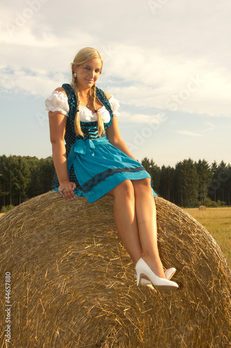 Frau blond Trachtenkleid Dirndl auf Strohballen
