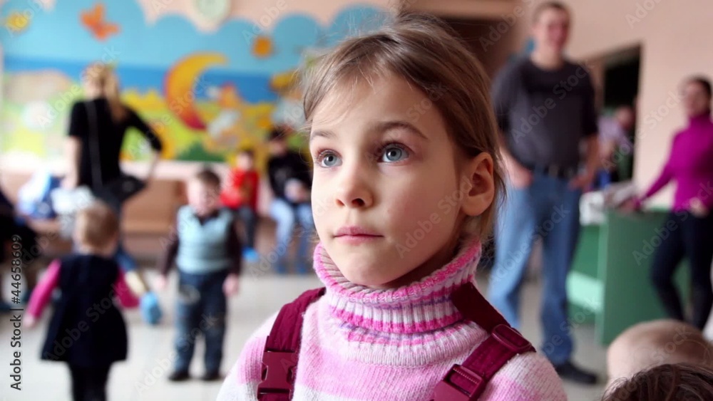 Little girl stand in childrens clinic among kids run around Little girl stand in childrens clinic among kids run around