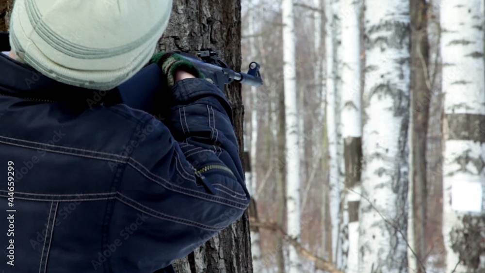 Young boy shoots paper target on birch Young boy shoots paper target on birch