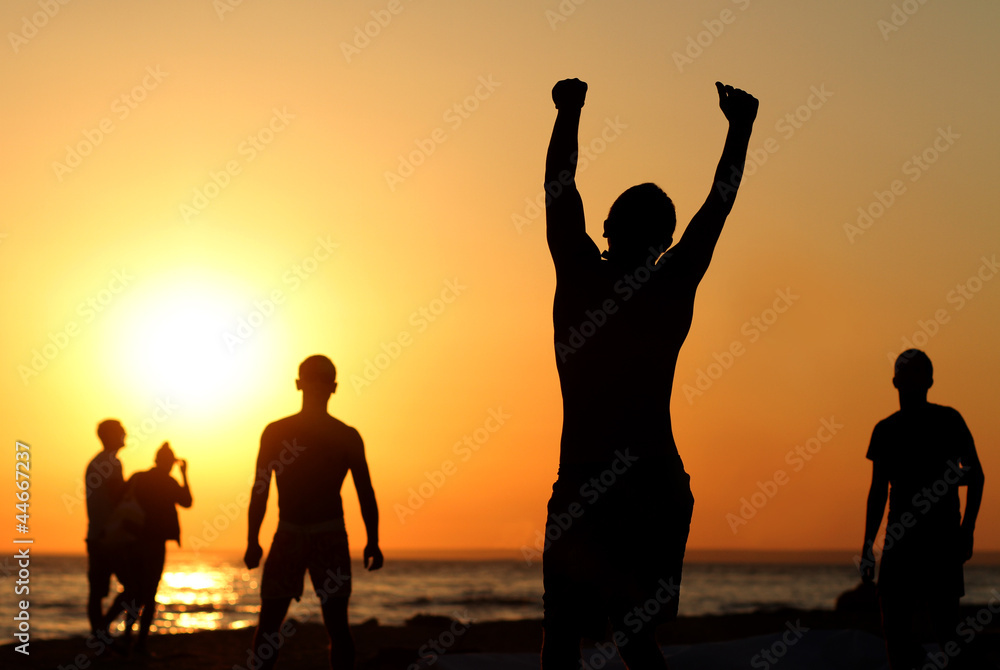 Fototapeta premium Silhouette of a happy person on the beach in summer. Group of friends enjoying vacation together