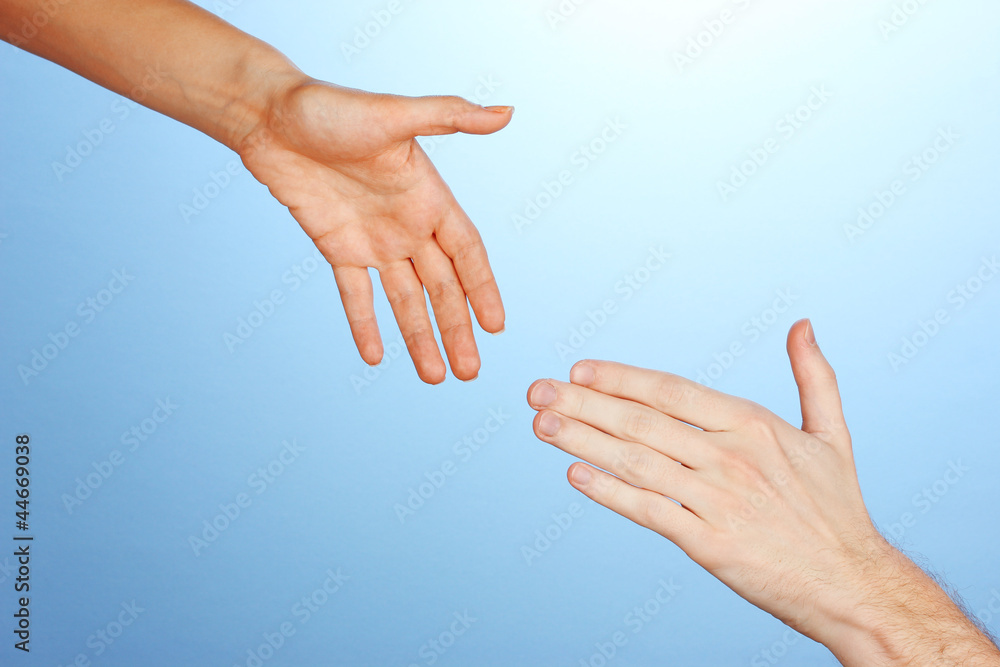 Women's hand goes to the man's hand on blue background