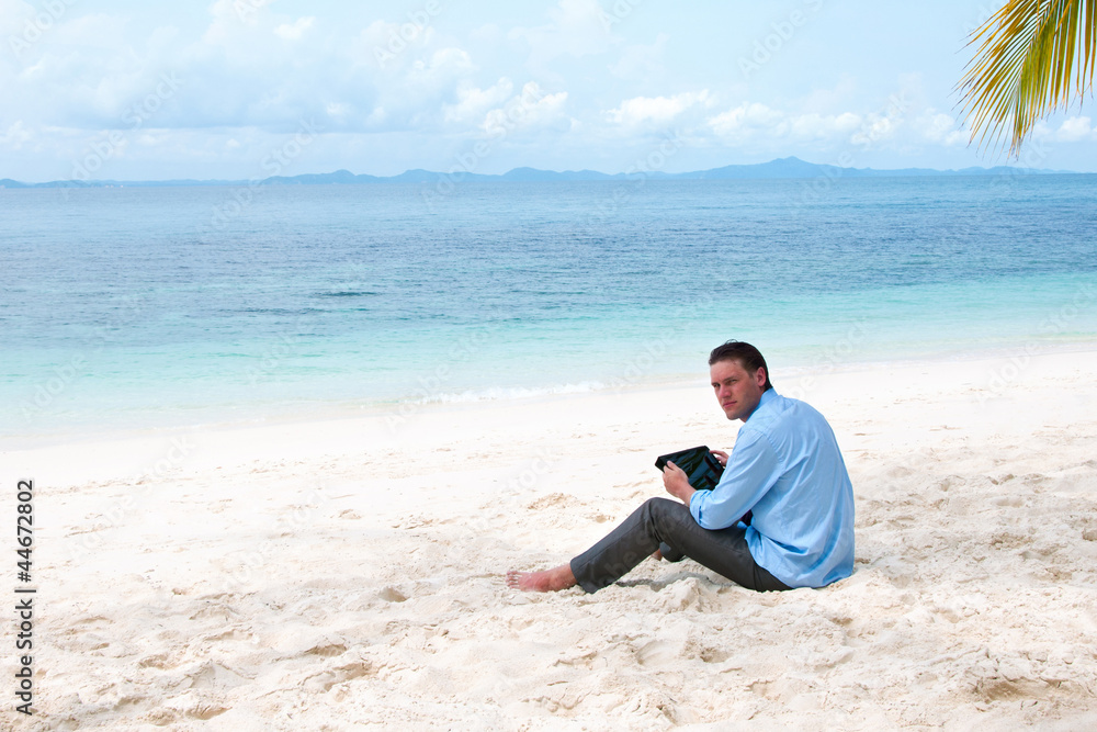 Business man sitting and working on the beach with tablet comput Business man sitting and working on the beach with tablet comput