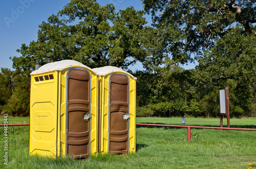 Two yellow portable toilets at a park photo