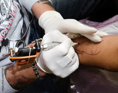Tattoo artist makes the tattoo on arm