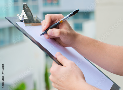 Fotografiet Businessman Holding A Clipboard And Writing