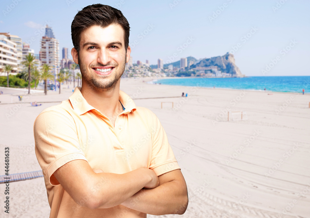 portrait of a handsome young man standing against a beach