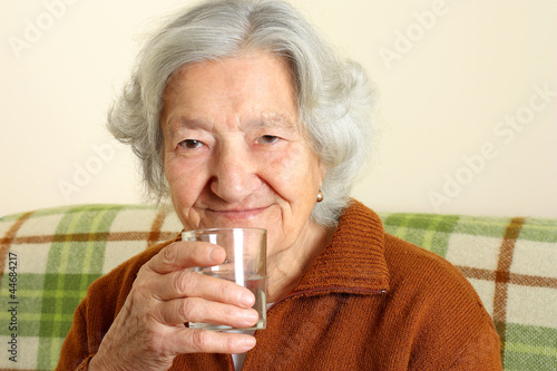 Grandmother drinks a glass of fresh water
